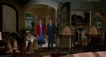 Movie still from “The Money Pit” (1986), directed by Richard Benjamin – A man and a woman standing in front of a mirror; Wide shot, Low angle