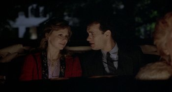 Movie still from “The Money Pit” (1986), directed by Richard Benjamin – A man and a woman sitting next to each other in the dark; Medium shot, Over the shoulder angle