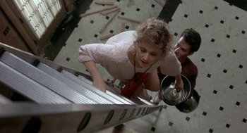 Movie still from “The Money Pit” (1986), directed by Richard Benjamin – A woman and a man looking down at a ladder; Medium shot, Overhead angle
