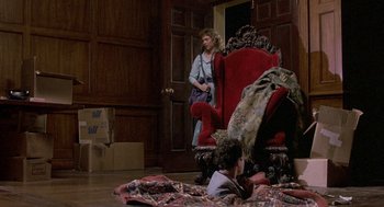 Movie still from “The Money Pit” (1986), directed by Richard Benjamin – A woman sitting in a chair in front of a boy; Wide shot, High angle