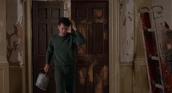 Movie still from “The Money Pit” (1986), directed by Richard Benjamin – A man in a green shirt is holding a bucket; Medium shot, Low angle