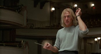 Movie still from “The Money Pit” (1986), directed by Richard Benjamin – A man with blonde hair is holding a conductor's baton; Medium shot, Low angle
