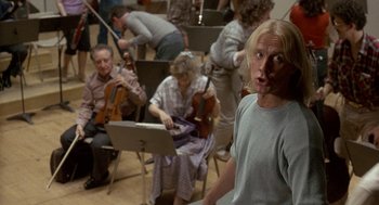 Movie still from “The Money Pit” (1986), directed by Richard Benjamin – A group of people sitting in a room with musical instruments; Medium shot, Low angle