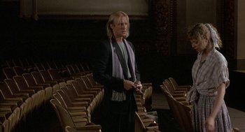 Movie still from “The Money Pit” (1986), directed by Richard Benjamin – A person standing in a room with some chairs; Medium shot, Low angle