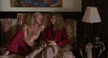 Movie still from “The Money Pit” (1986), directed by Richard Benjamin – A man and a woman sitting on a couch together; Medium shot, High angle