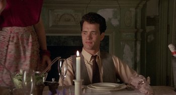 Movie still from “The Money Pit” (1986), directed by Richard Benjamin – A man sitting at a dinner table with a lit candle; Close Up shot, Over the shoulder angle