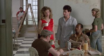 Movie still from “The Money Pit” (1986), directed by Richard Benjamin – A group of people standing around a table; Medium shot, Over the shoulder angle