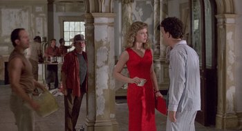 Movie still from “The Money Pit” (1986), directed by Richard Benjamin – A woman in a red dress talking to two men; Wide shot, Over the shoulder angle