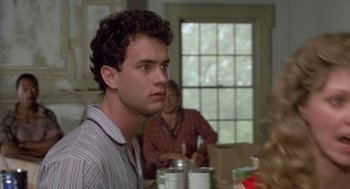 Movie still from “The Money Pit” (1986), directed by Richard Benjamin – A man sitting at a table with a cup in his hand; Close Up shot, Over the shoulder angle