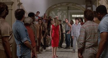 Movie still from “The Money Pit” (1986), directed by Richard Benjamin – A woman in a red dress standing in front of a group of men; Wide shot, Low angle