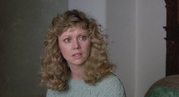 Movie still from “The Money Pit” (1986), directed by Richard Benjamin – A woman with long blonde curly hair looking at the camera; Close Up shot, Over the shoulder angle