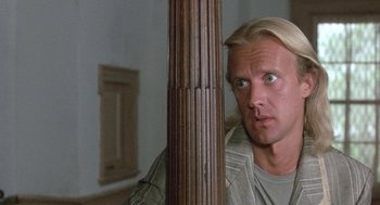 Movie still from “The Money Pit” (1986), directed by Richard Benjamin – A man standing next to a wooden pole in a room; Close Up shot, Over the shoulder angle
