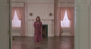 Movie still from “The Money Pit” (1986), directed by Richard Benjamin – A woman in a pink dress standing in a living room; Wide shot, Low angle