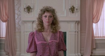 Movie still from “The Money Pit” (1986), directed by Richard Benjamin – A woman in a pink dress standing in front of a fireplace; Medium shot, Low angle