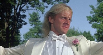 Movie still from “The Money Pit” (1986), directed by Richard Benjamin – A man in a white tuxedo with a flower in his hair; Close Up shot, Low angle