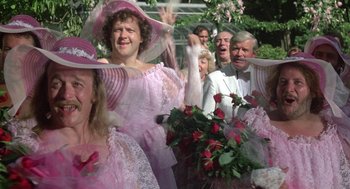 Movie still from “The Money Pit” (1986), directed by Richard Benjamin – A group of people dressed up in pink and white costumes; Medium shot, Over the shoulder angle