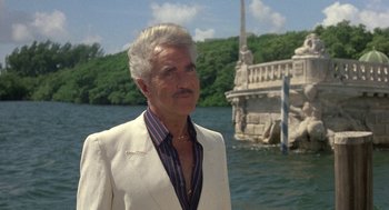 Movie still from “The Money Pit” (1986), directed by Richard Benjamin – An older man standing in front of a body of water; Medium shot, Over the shoulder angle