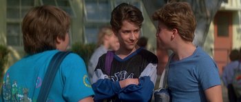 Movie still from “The Monster Squad” (1987), directed by Fred Dekker – A young boy with his arms crossed and a backpack; Close Up shot, Over the shoulder angle
