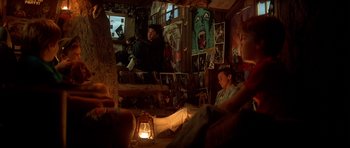 Movie still from “The Monster Squad” (1987), directed by Fred Dekker – Two people sitting on a couch in front of a lamp; Wide shot, Low angle