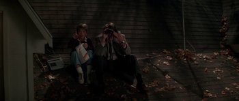 Movie still from “The Monster Squad” (1987), directed by Fred Dekker – A couple of people sitting on the side of a road; Medium shot, High angle