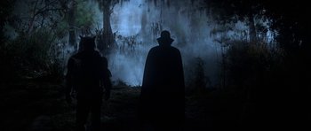 Movie still from “The Monster Squad” (1987), directed by Fred Dekker – A man in a black cape standing in front of a tree; Wide shot, Low angle