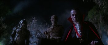 Movie still from “The Monster Squad” (1987), directed by Fred Dekker – A man dressed as a vampire standing next to a statue; Medium shot, Low angle