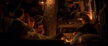 Movie still from “The Monster Squad” (1987), directed by Fred Dekker – A group of people sitting in a room with a tree; Wide shot, High angle