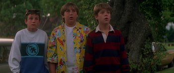 Movie still from “The Monster Squad” (1987), directed by Fred Dekker – Two young men standing next to each other in front of a tree; Medium shot, Low angle
