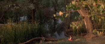 Movie still from “The Monster Squad” (1987), directed by Fred Dekker – A child sitting on the ground next to a body of water; Extreme Wide shot, High angle