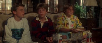 Movie still from “The Monster Squad” (1987), directed by Fred Dekker – Two young boys sitting in a living room next to each other; Medium shot, Over the shoulder angle