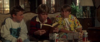 Movie still from “The Monster Squad” (1987), directed by Fred Dekker – Two young boys sitting on a couch reading books; Medium shot, High angle