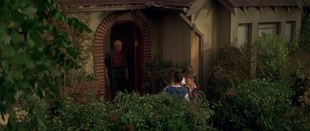 Movie still from “The Monster Squad” (1987), directed by Fred Dekker – A man standing in front of a house with a woman and a man; Wide shot, High angle