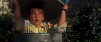 Movie still from “The Monster Squad” (1987), directed by Fred Dekker – A young boy wearing a hat in a metal bucket; Close Up shot, Low angle