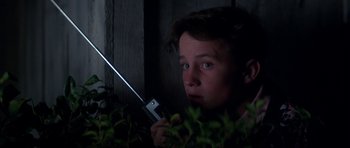 Movie still from “The Monster Squad” (1987), directed by Fred Dekker – A young man holding a flashlight in a dark room; Close Up shot, Low angle