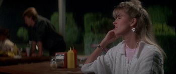 Movie still from “The Monster Squad” (1987), directed by Fred Dekker – A woman sitting at a table in front of some condiments; Close Up shot, Over the shoulder angle