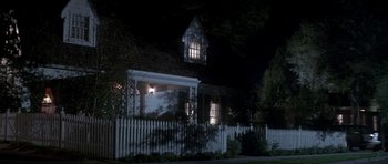 Movie still from “The Monster Squad” (1987), directed by Fred Dekker – A house with a white picket fence in front of it at night; Extreme Wide shot, Low angle
