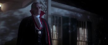 Movie still from “The Monster Squad” (1987), directed by Fred Dekker – A man dressed up as a vampire standing in front of a house; Medium shot, Low angle