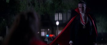 Movie still from “The Monster Squad” (1987), directed by Fred Dekker – A person in a suit and tie standing next to an umbrella; Medium shot, Over the shoulder angle