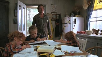 Movie still from “The Mosquito Coast” (1986), directed by Peter Weir – A group of people sitting at a table doing homework; Medium shot, Low angle