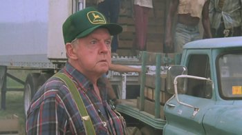 Movie still from “The Mosquito Coast” (1986), directed by Peter Weir – An older man wearing a john deere hat; Close Up shot, Over the shoulder angle