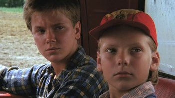 Movie still from “The Mosquito Coast” (1986), directed by Peter Weir – Two young boys sitting next to each other in a room; Close Up shot, Low angle