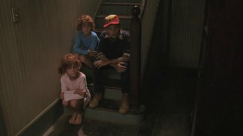 Movie still from “The Mosquito Coast” (1986), directed by Peter Weir – A group of kids sitting on the steps of a house; Wide shot, High angle
