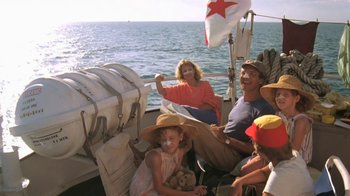 Movie still from “The Mosquito Coast” (1986), directed by Peter Weir – A group of people sitting on a boat in the water; Wide shot, Low angle