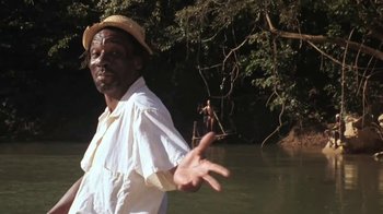 Movie still from “The Mosquito Coast” (1986), directed by Peter Weir – A man standing in the water near a body of water; Medium shot, Low angle