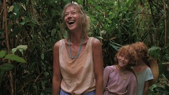 Movie still from “The Mosquito Coast” (1986), directed by Peter Weir – A woman and a girl laughing in front of a bush; Medium shot, Low angle