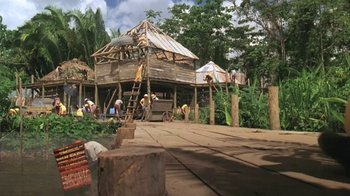 Movie still from “The Mosquito Coast” (1986), directed by Peter Weir – A group of people standing around a wooden structure; Extreme Wide shot, Low angle
