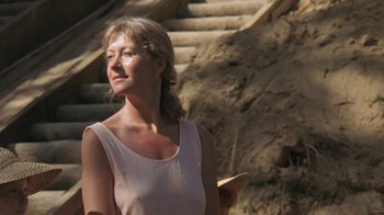 Movie still from “The Mosquito Coast” (1986), directed by Peter Weir – A woman standing next to a set of stairs; Close Up shot, Low angle