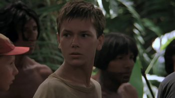 Movie still from “The Mosquito Coast” (1986), directed by Peter Weir – A young man in a tan shirt is in the woods; Close Up shot, Low angle