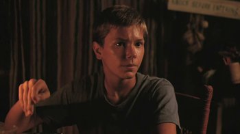 Movie still from “The Mosquito Coast” (1986), directed by Peter Weir – A young man sitting in front of a curtain; Close Up shot, Low angle
