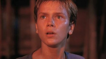 Movie still from “The Mosquito Coast” (1986), directed by Peter Weir – A young boy with wet hair stares into the distance; Close Up shot, Low angle